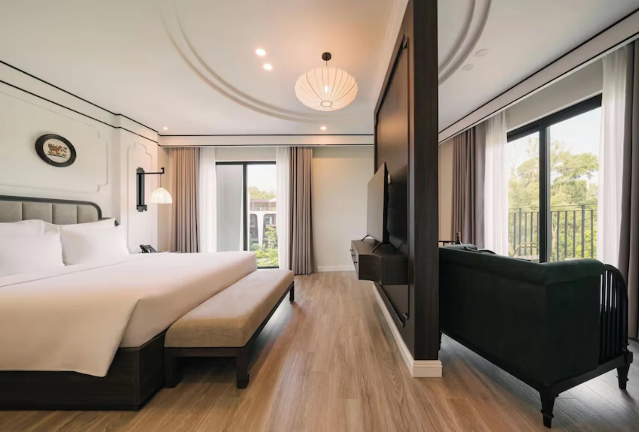 Phòng ngủ giường đôi có sofa và cửa kính nhìn ra vườn tại Soc Village Wellness & Retreat