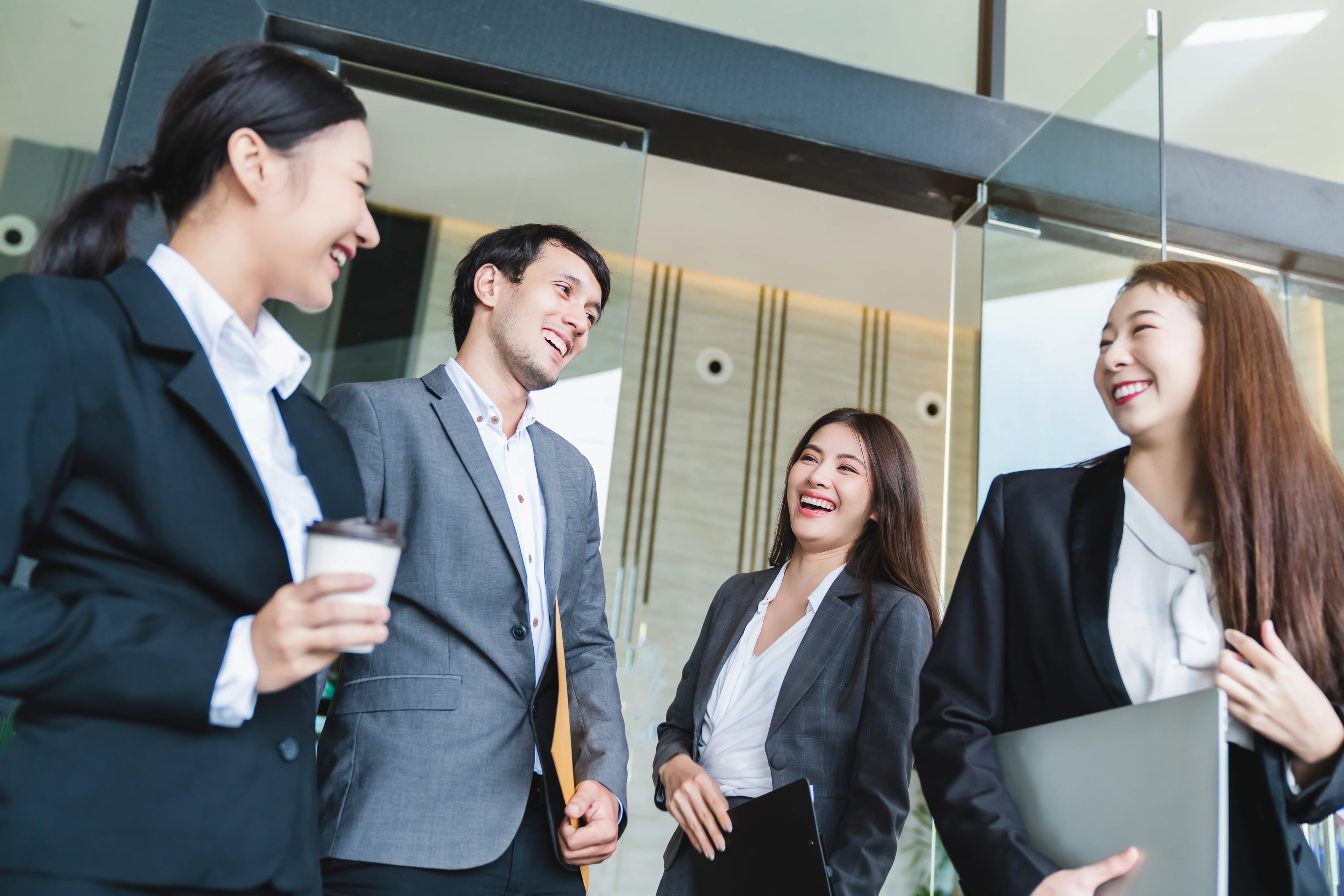Group smart young asian businessmale female formal dress walking pass modern office entrance with confident happiness