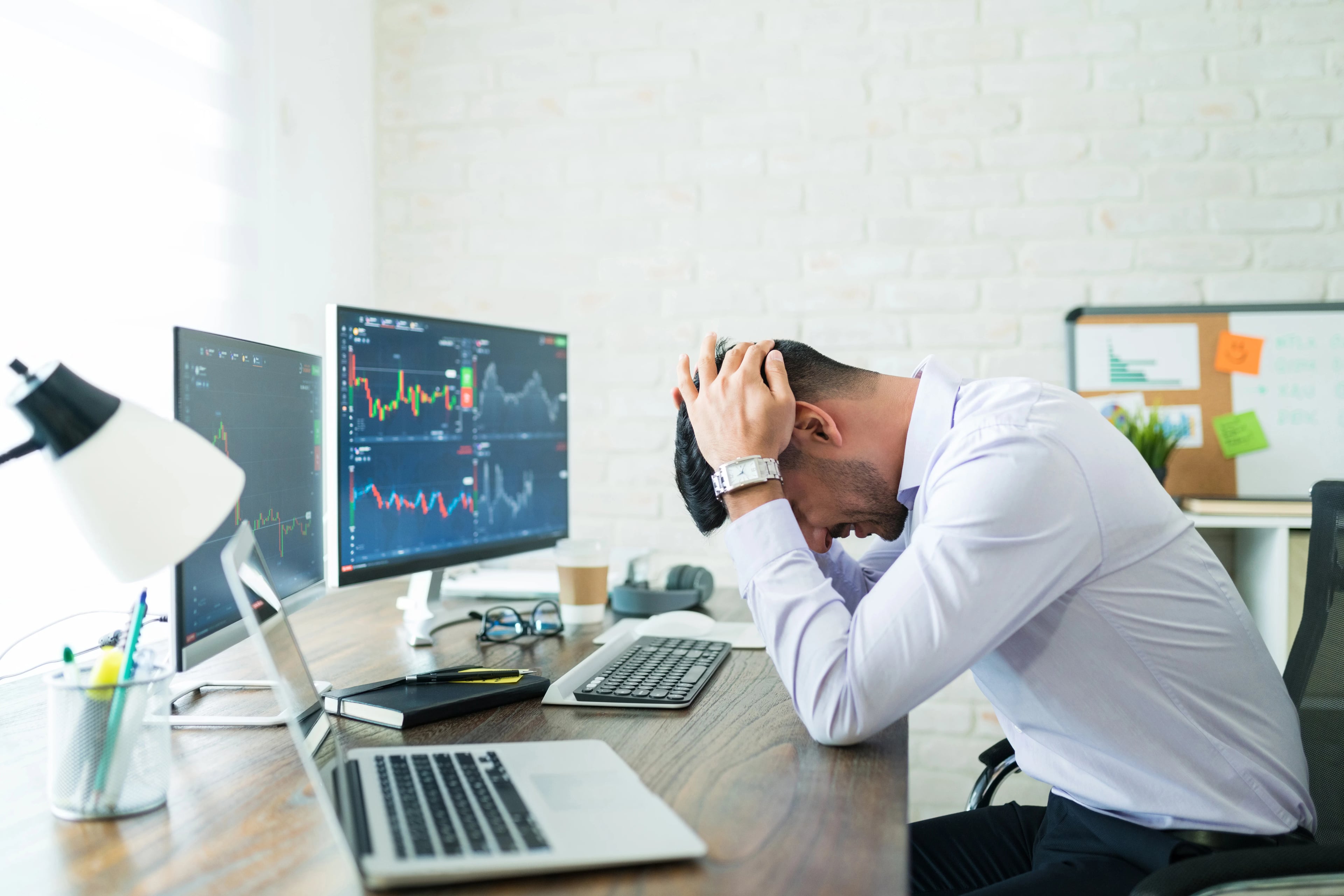 Side view stressed young broker sitting with head hands desk while working from home